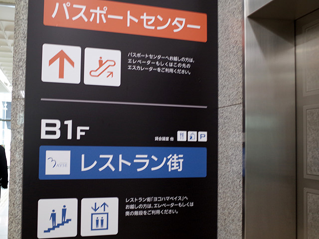 ビル内の案内板。2Fパスポートセンター、B1Fレストラン街と書かれてる ビル内の案内板。2Fパスポートセンター、B1Fレストラン街と書かれてる